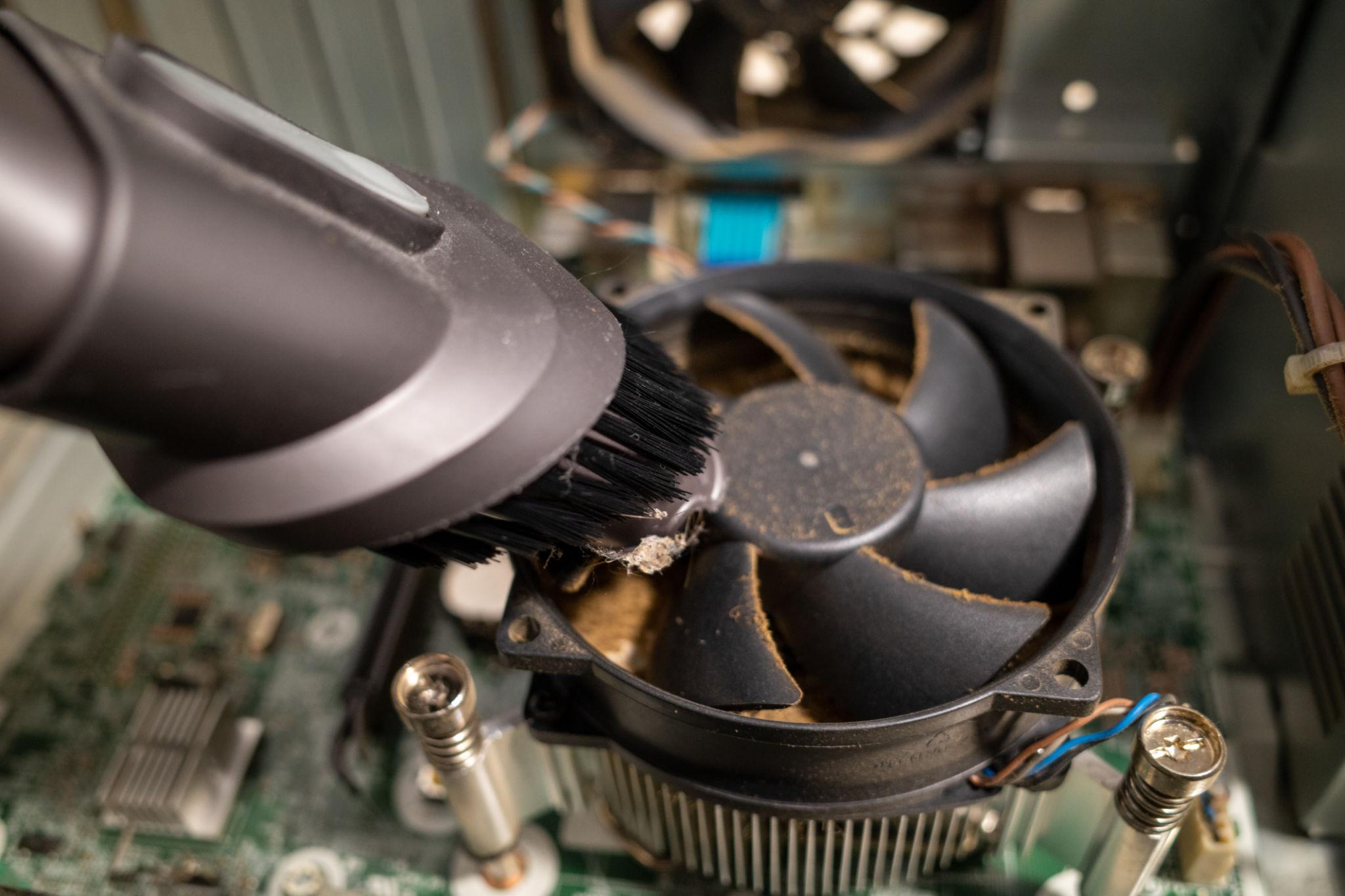 Technician servicing the inside of a desktop computer to improve cooling and performance